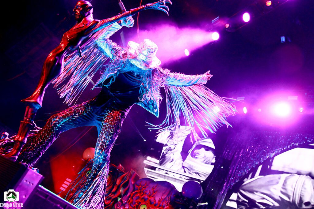 Performer in vibrant costume on stage, dancing.