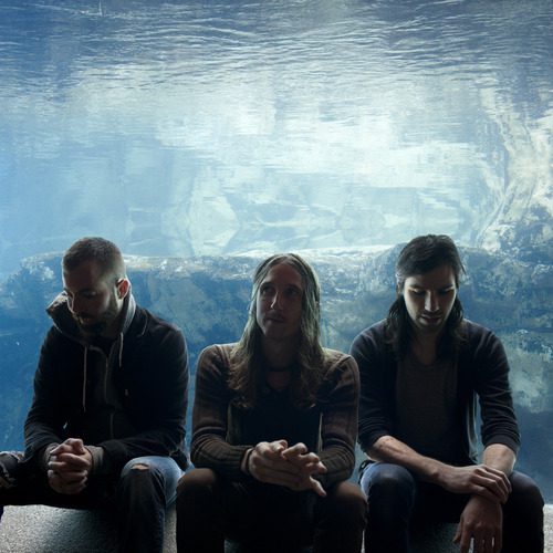 Three people sitting in front of aquarium.