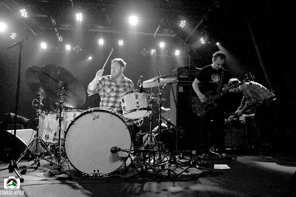 Band performing live on stage with instruments.