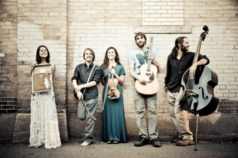 Band with instruments against a brick wall.