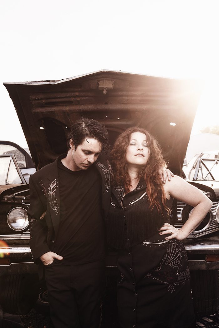 Two people standing by an open car.