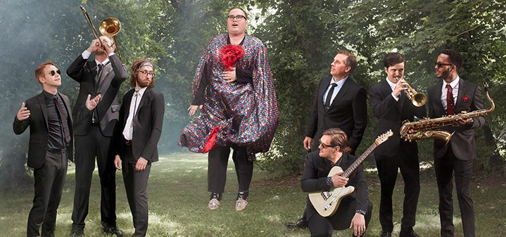 Band posing outdoors with musical instruments.