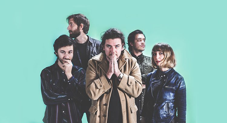 Five people posing against a turquoise background.