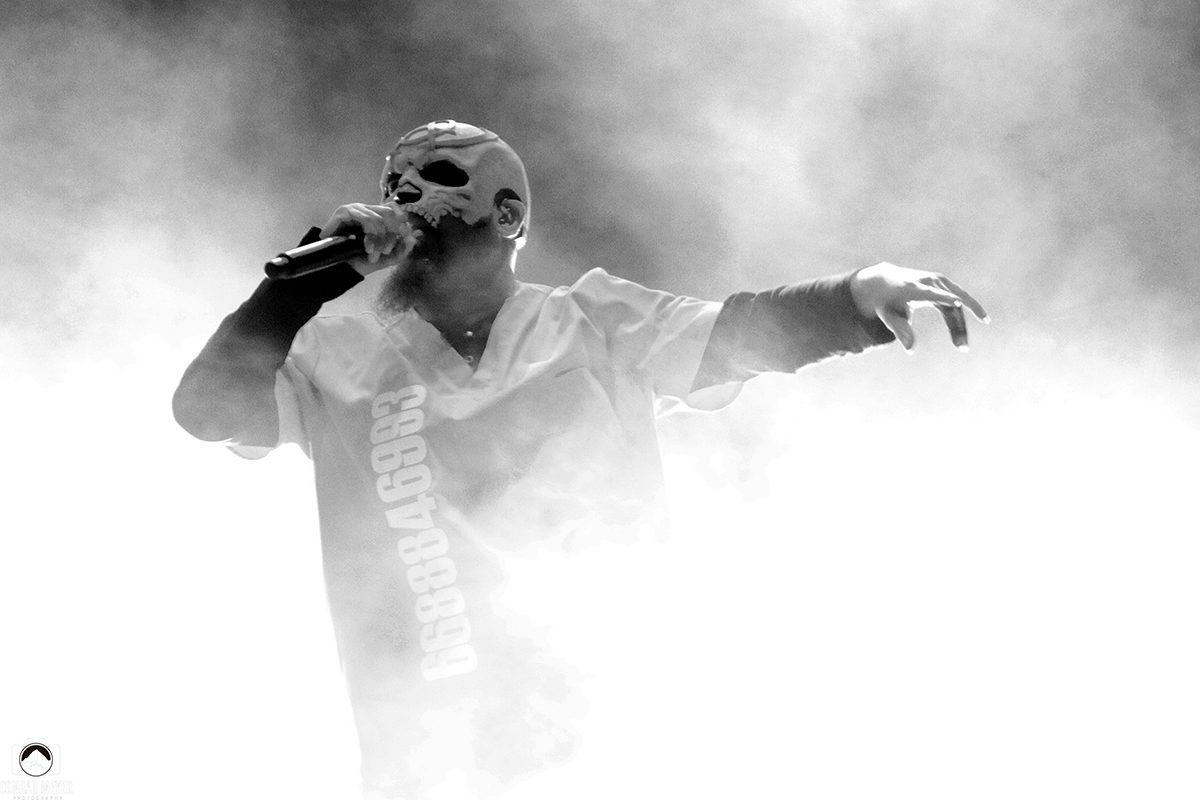 Singer in mask performing amidst smoke.