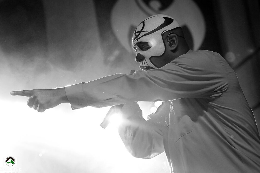 Masked performer pointing during a concert.