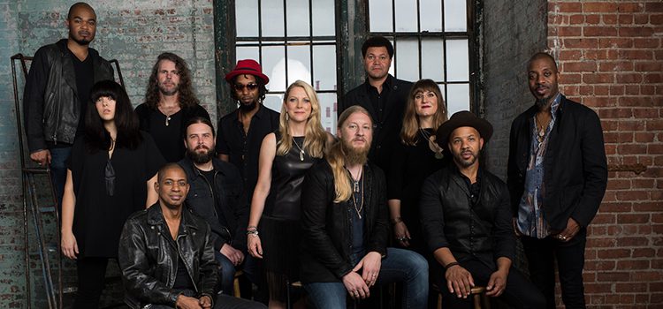 Group of musicians posing against brick wall.