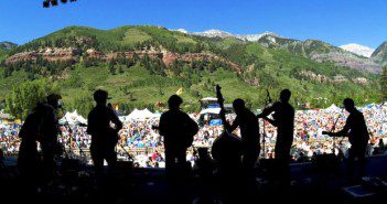 Silhouetted band performing at outdoor festival.
