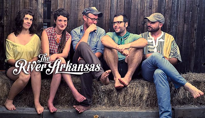 Five people sitting on hay bales.