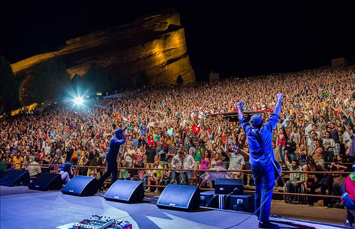 Concert crowd at outdoor amphitheater, night performance.