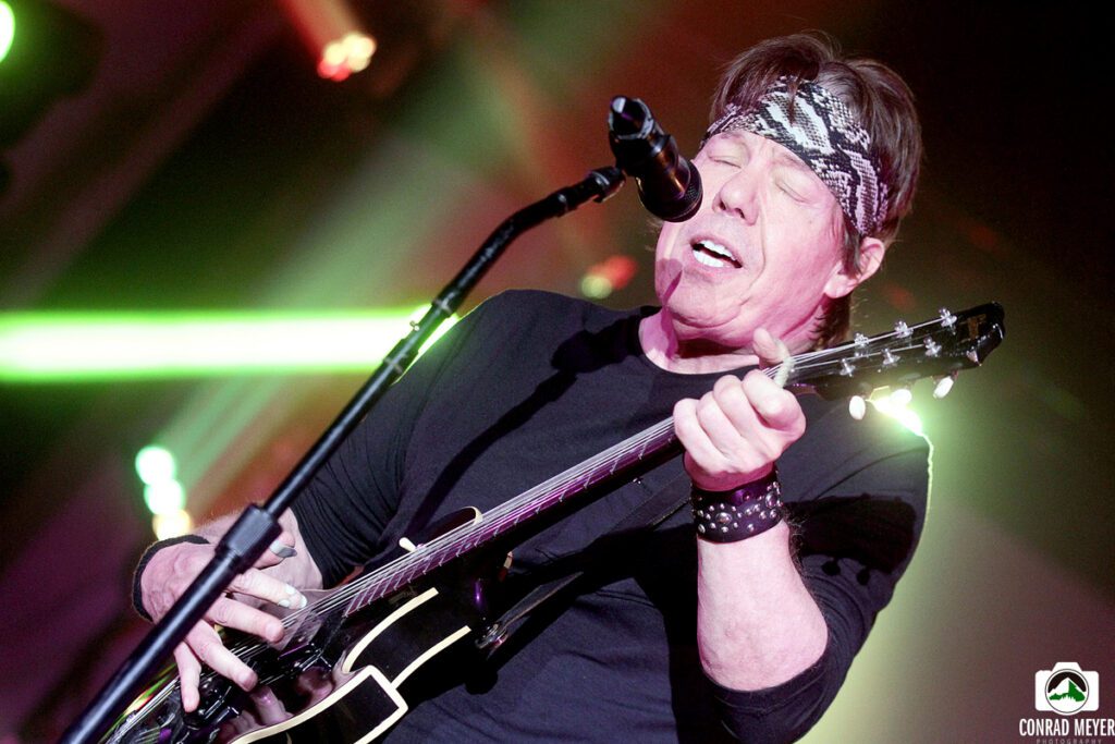 Musician passionately playing guitar on stage.