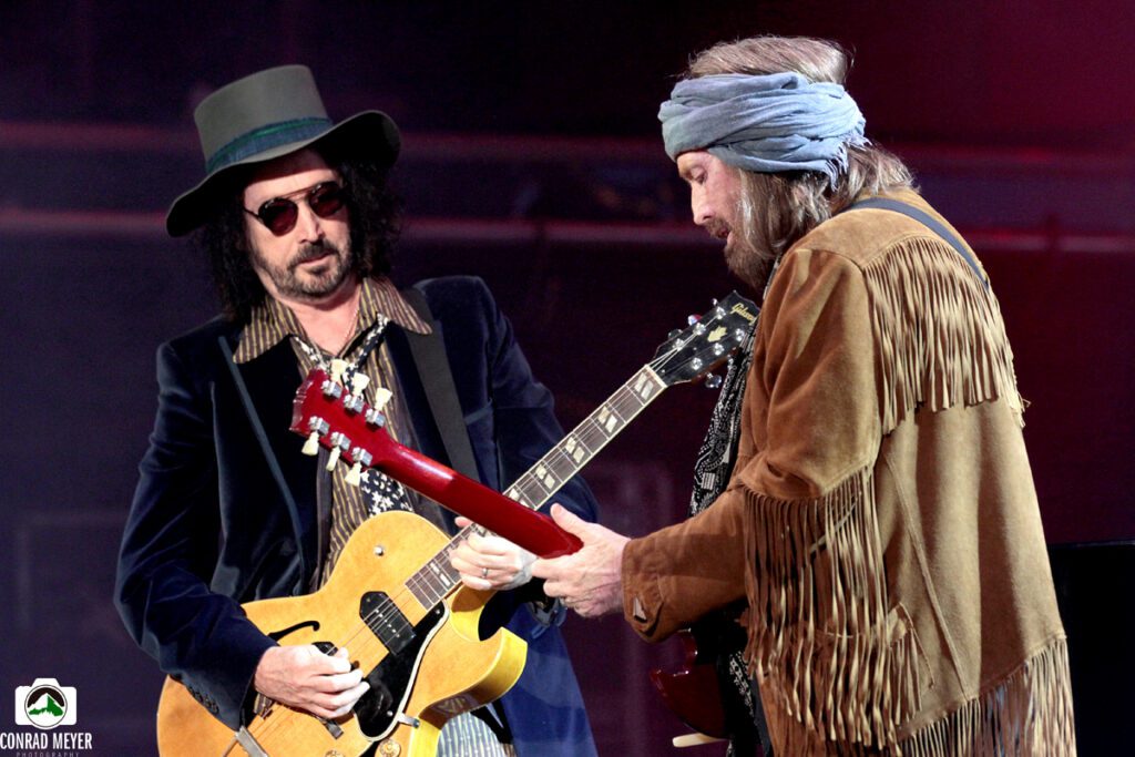Two musicians playing guitars on stage.