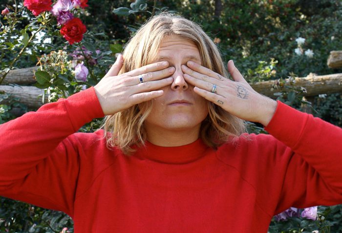 Person covering eyes in a garden.