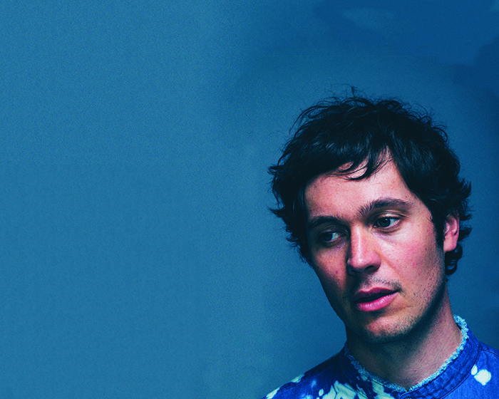 Man in blue tie-dye shirt, blue background.