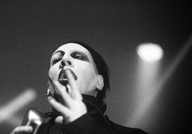 Singer performing on stage in dramatic lighting.
