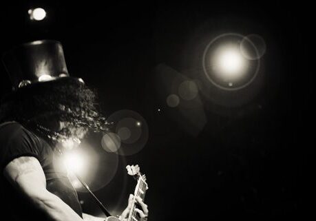 Guitarist performing on stage with spotlight.