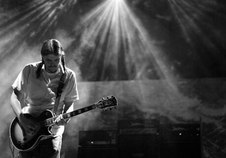 Guitarist performing under dramatic stage lighting.