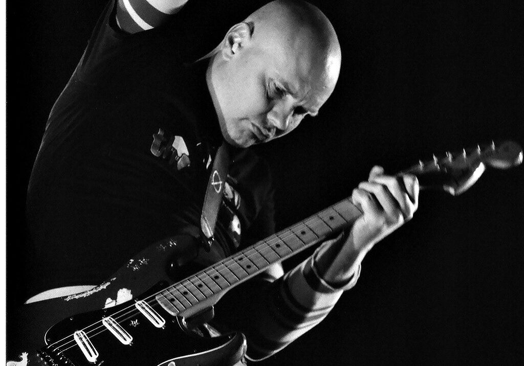 Guitarist performing energetically on stage.