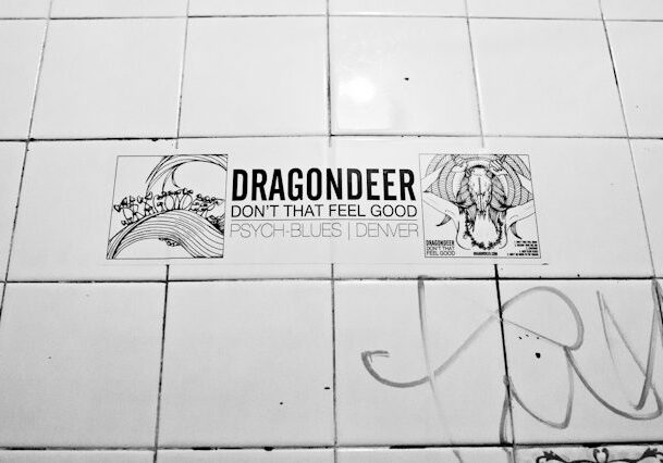 Band poster on tiled wall with graffiti.
