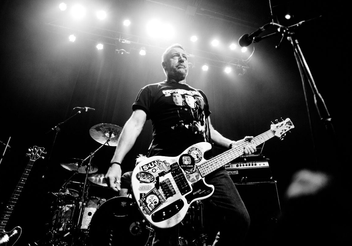 Musician playing guitar on stage, black and white.