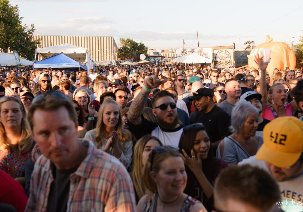 Crowd enjoying outdoor festival under clear sky.