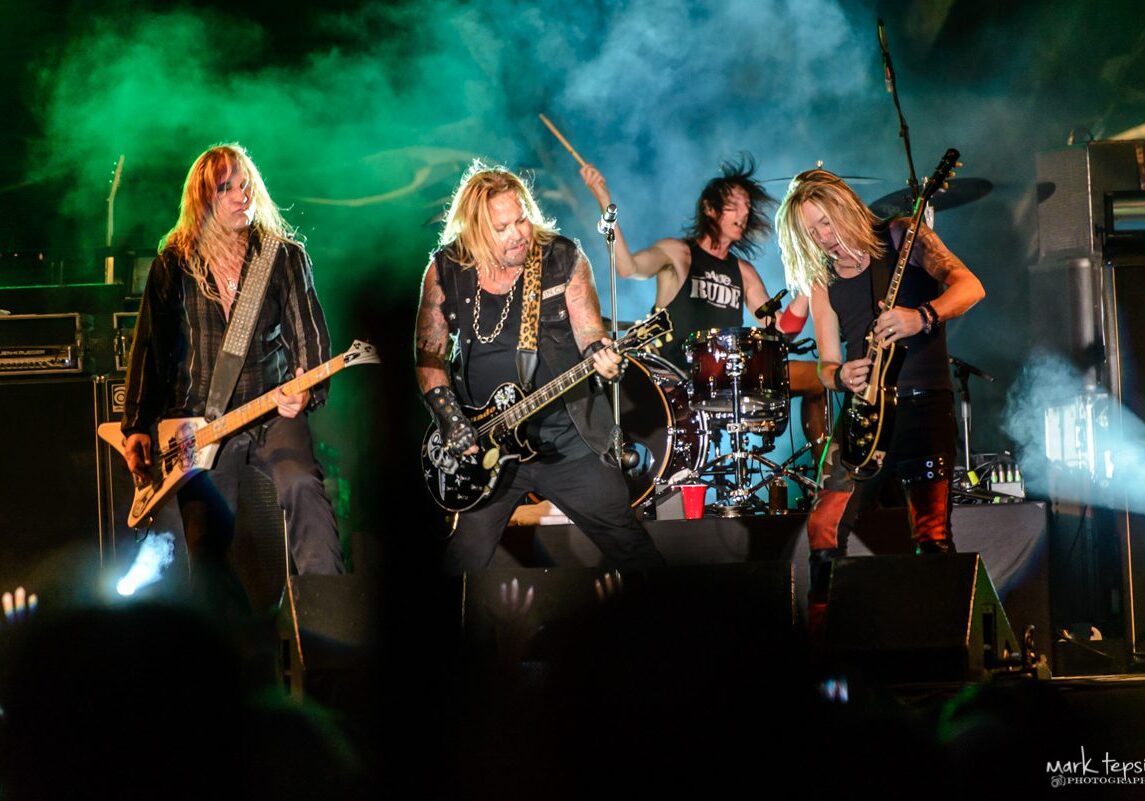 Rock band performing energetically on stage.