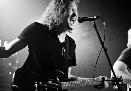 Musician performing passionately under a chandelier.