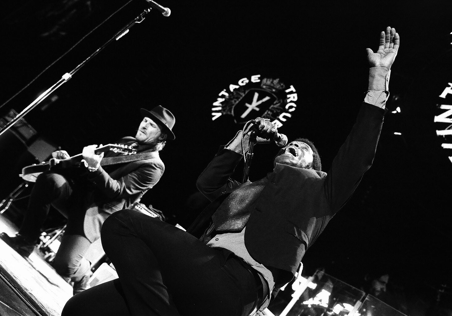 Musicians performing energetically on stage in black and white.