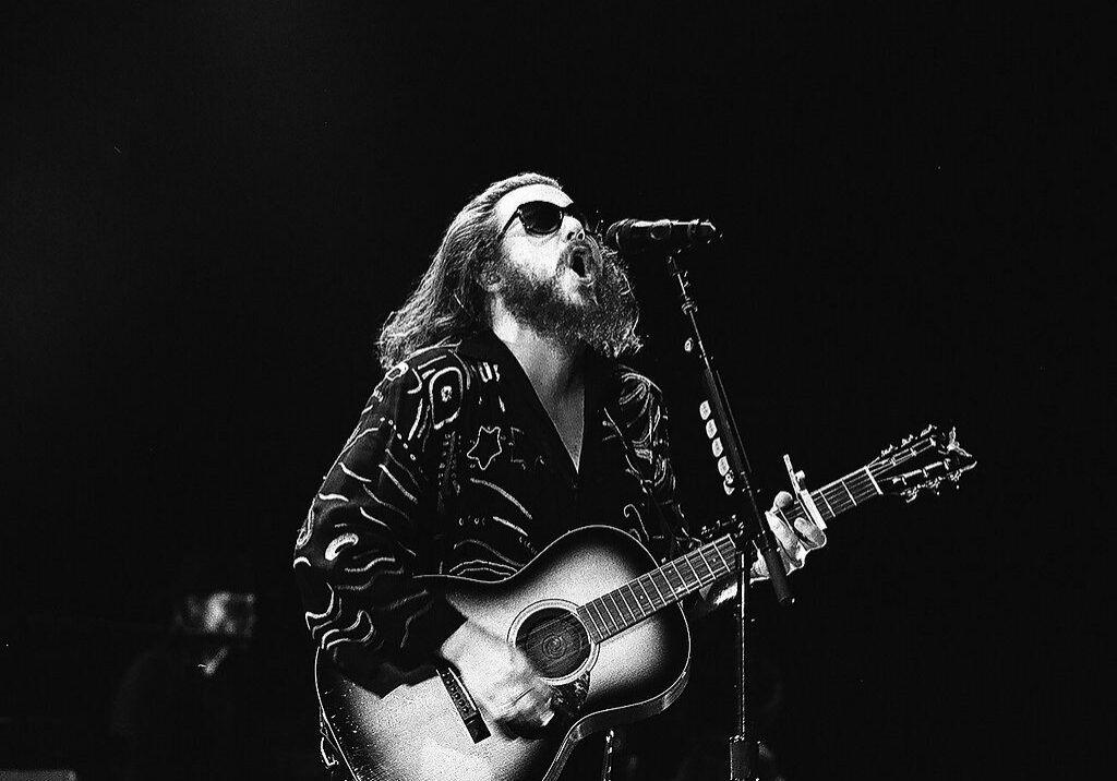 Musician performing with guitar on stage.