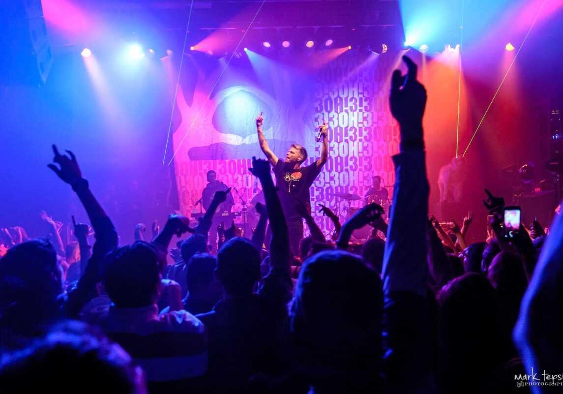 Concert crowd with vibrant stage lighting.
