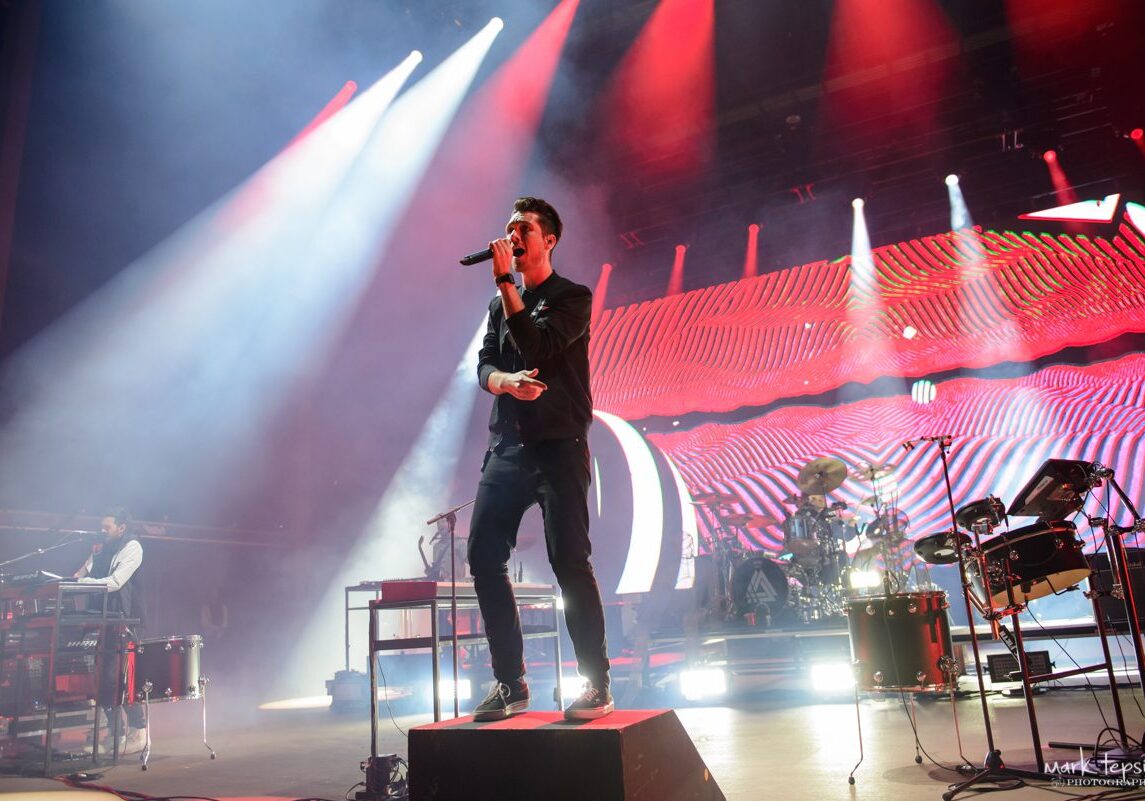 Band performing live on stage with lights.