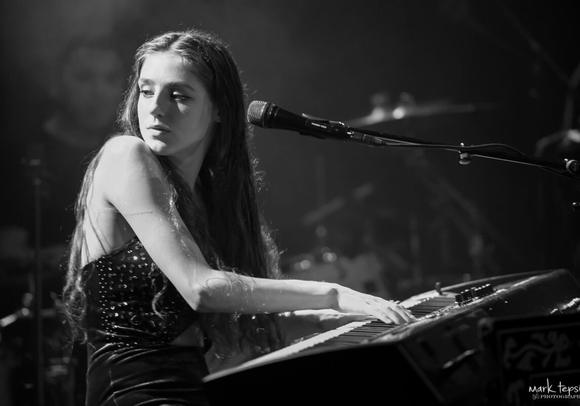 Young woman playing keyboard on stage.