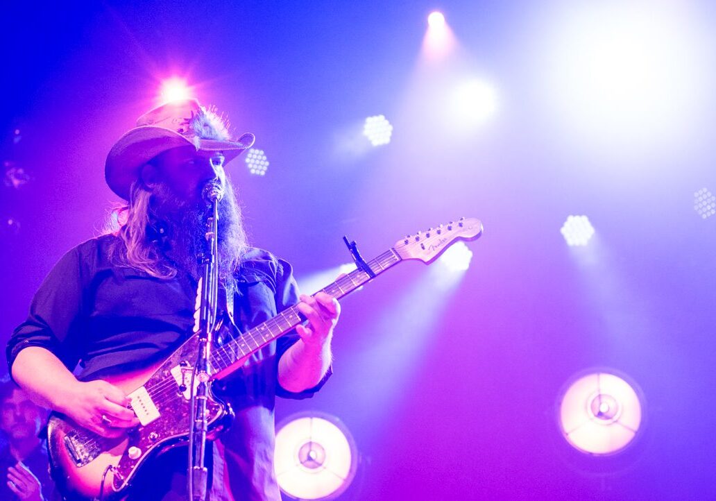 Guitarist performing on stage with vibrant lights.