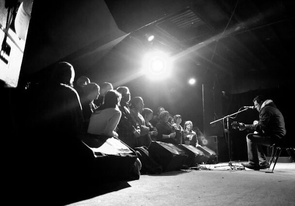 Musician performing on stage to audience.