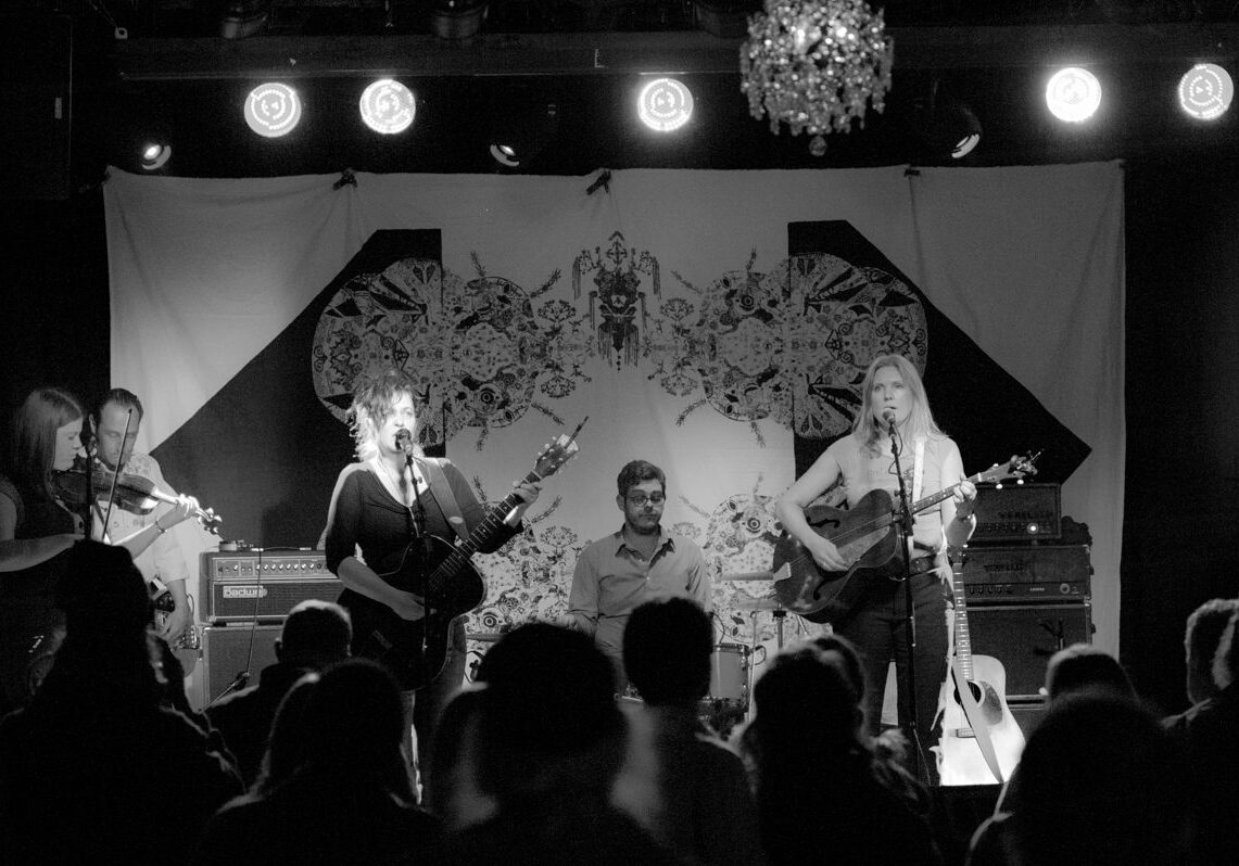 Band performing on stage with audience watching.