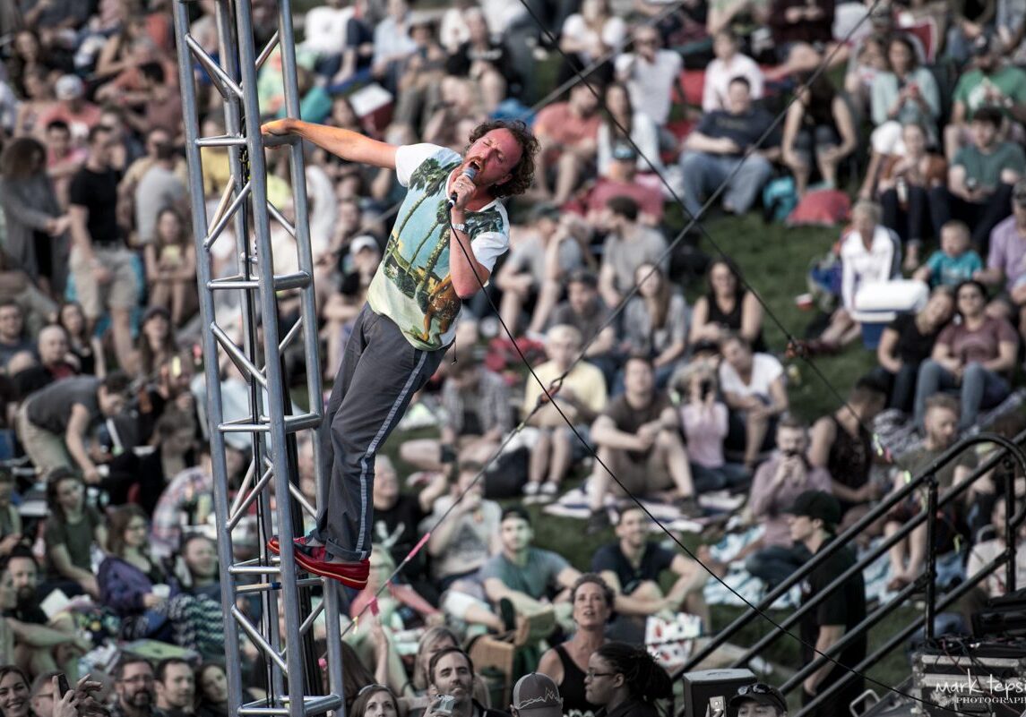 Performer climbing structure at outdoor concert.