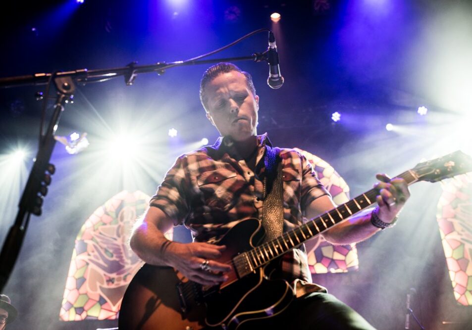 Guitarist performing under colorful stage lights.