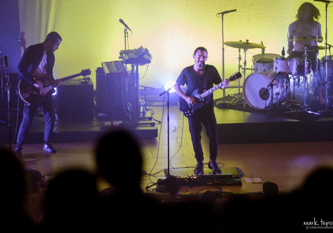 Band performing on stage with colorful lighting.