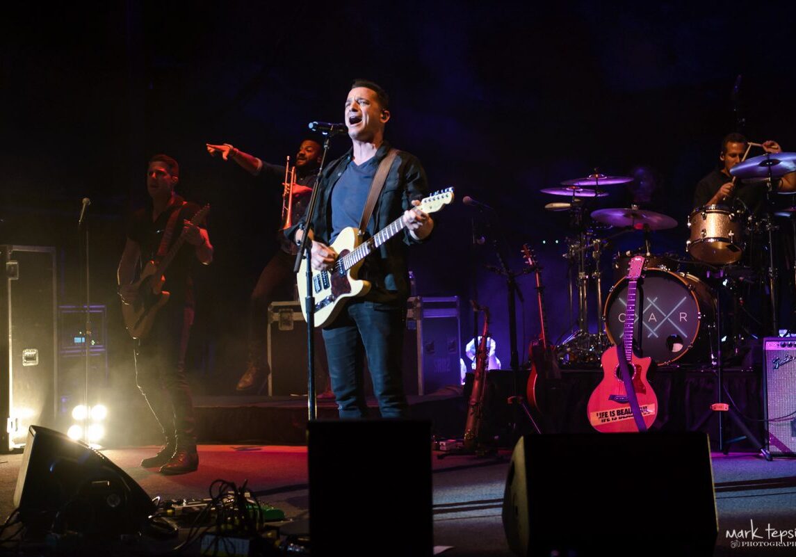 Band performing live on stage with instruments.