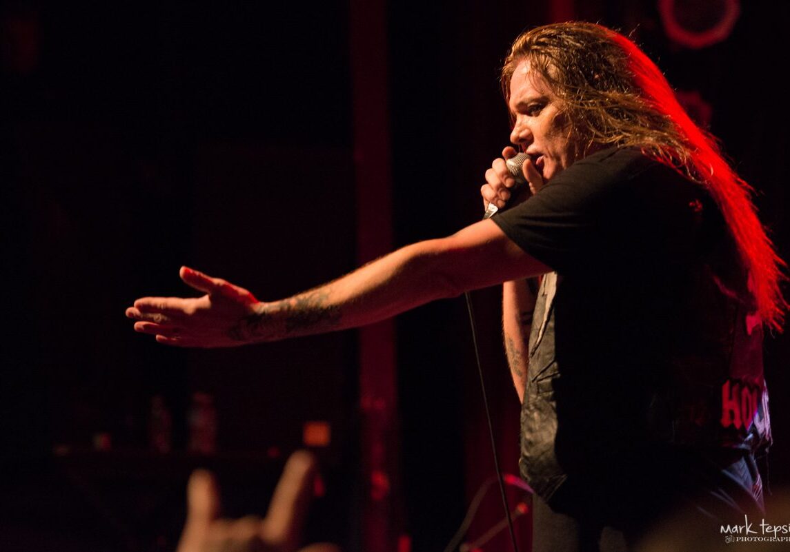 Singer performing passionately on stage with microphone.