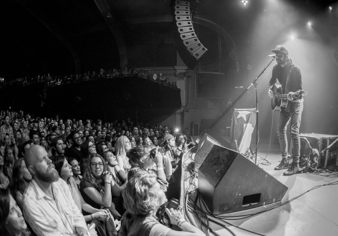 Musician performing on stage to enthusiastic audience.