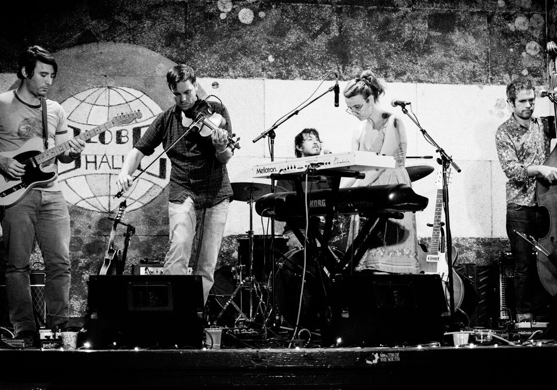 Band performing on stage with various instruments.