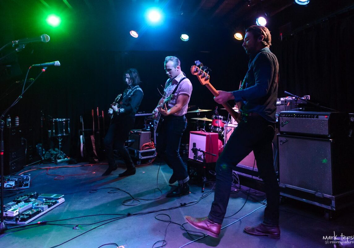 Band performing live on stage with instruments.