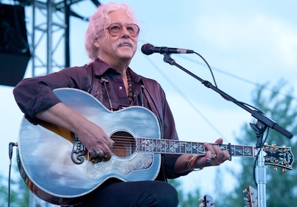 Musician playing acoustic guitar on stage.