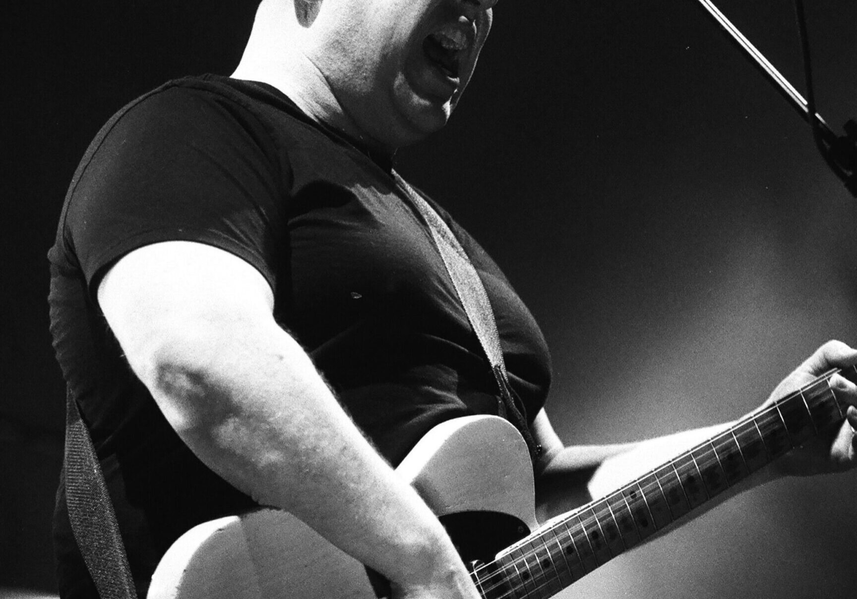 Musician passionately playing guitar on stage.