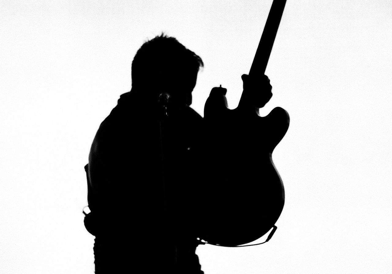 Silhouette of guitarist holding an electric guitar.