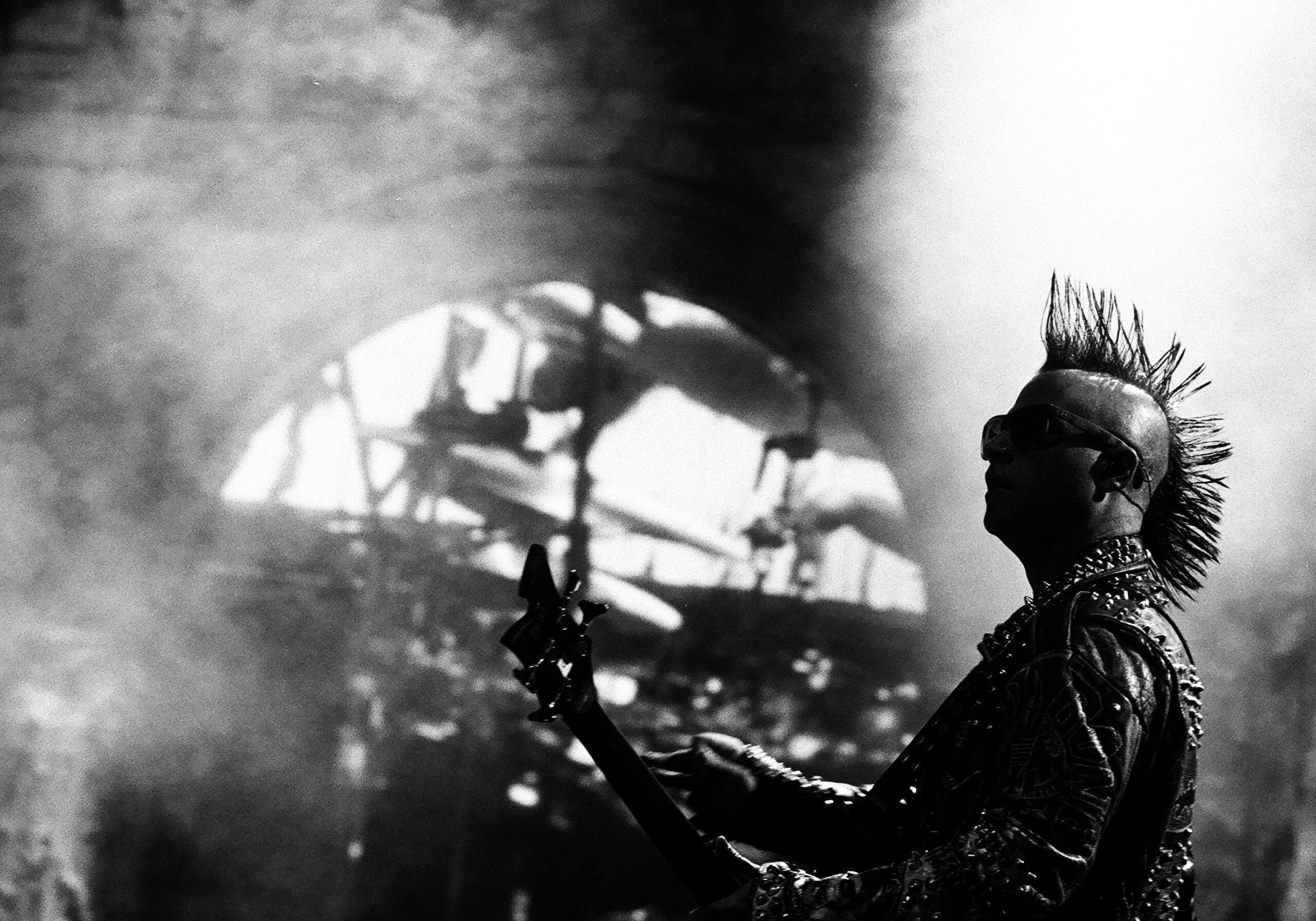 Punk musician playing guitar on stage.