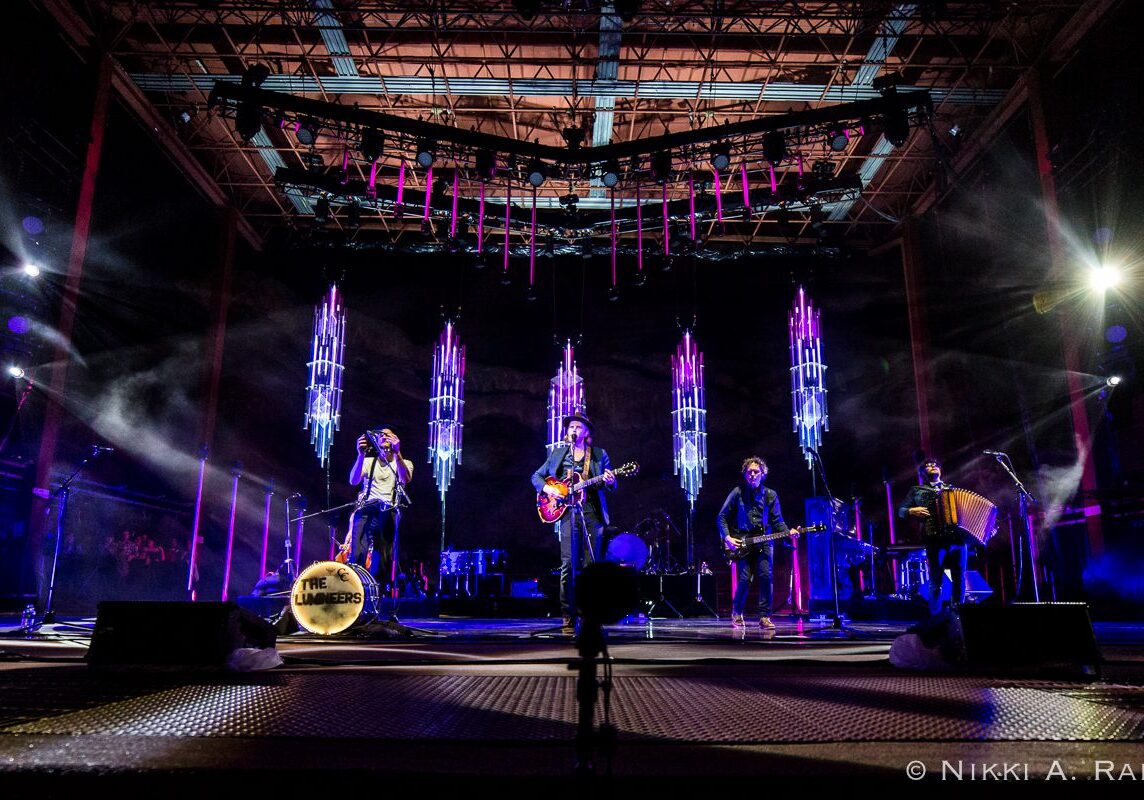Band performing on stage with vibrant lights.