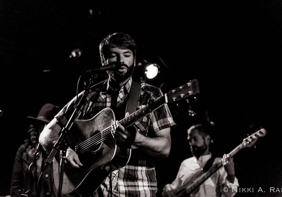 Musician performing on stage with guitar.