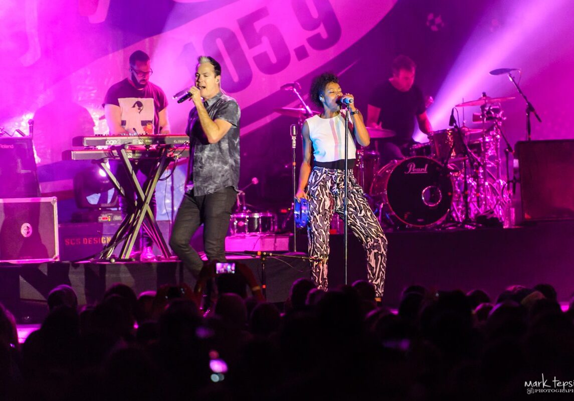 Singers performing on stage with band.