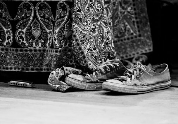 Worn sneakers and harmonica on patterned fabric.